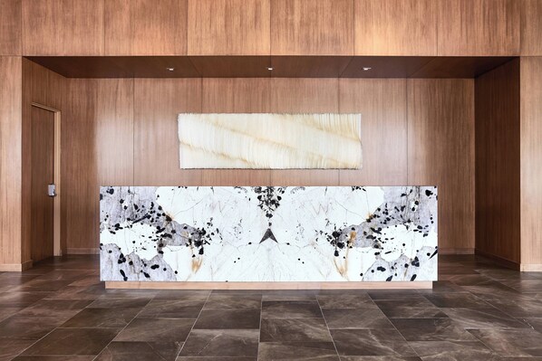 A reception desk with a marble top and a large abstract painting above it.