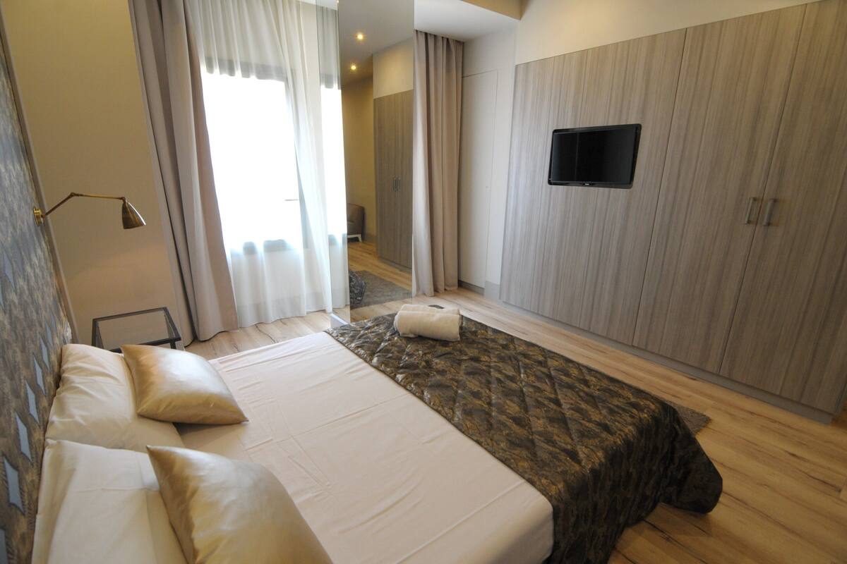 Una habitación de hotel con una cama grande, un televisor de pantalla plana en la pared y un armario.
