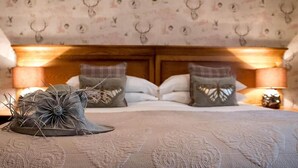A bedroom with a wooden headboard, patterned wallpaper, and a decorative deer head on the wall. - The Coach House Inn (Chester)