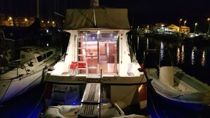 Een boot in een jachthaven, met een overdekte zithoek en een kleine tafel.