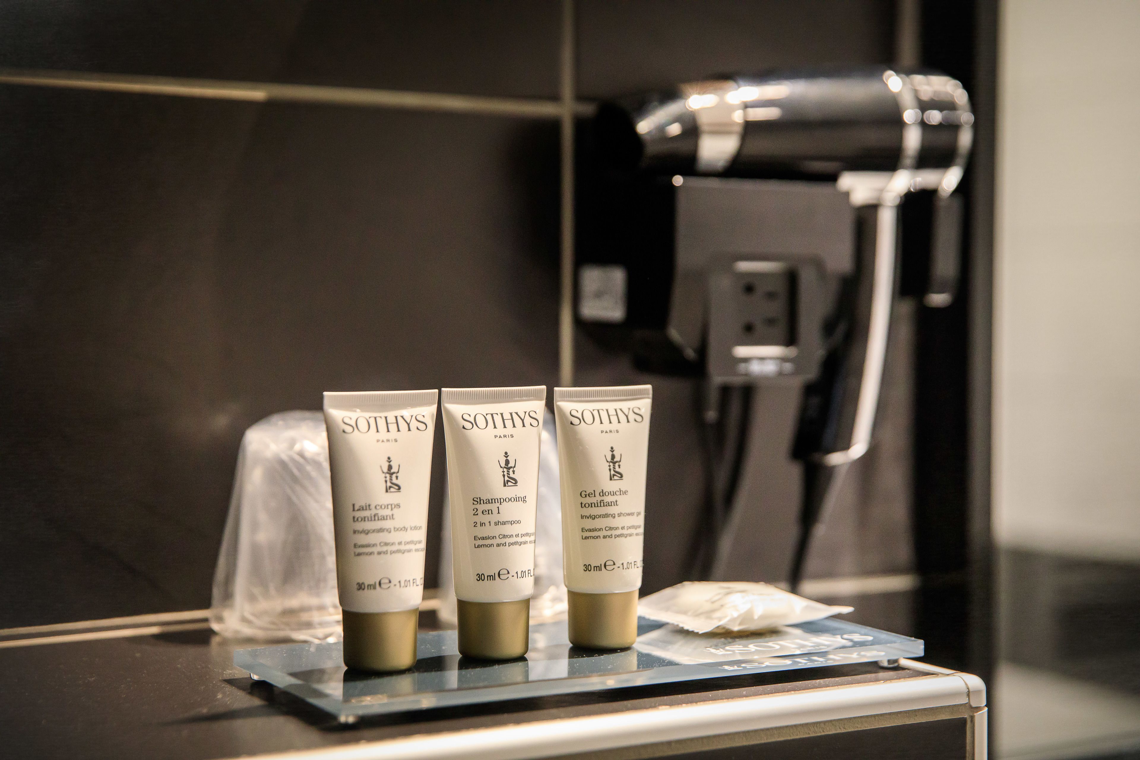 Drie Sothys shampoo flessen op een badkamermeubel, met een haardroger op de achtergrond.