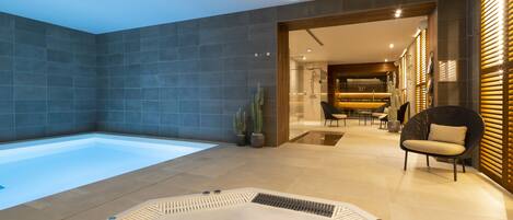 A modern bathroom with a large bathtub, a shower area, and a seating area with chairs and a table.