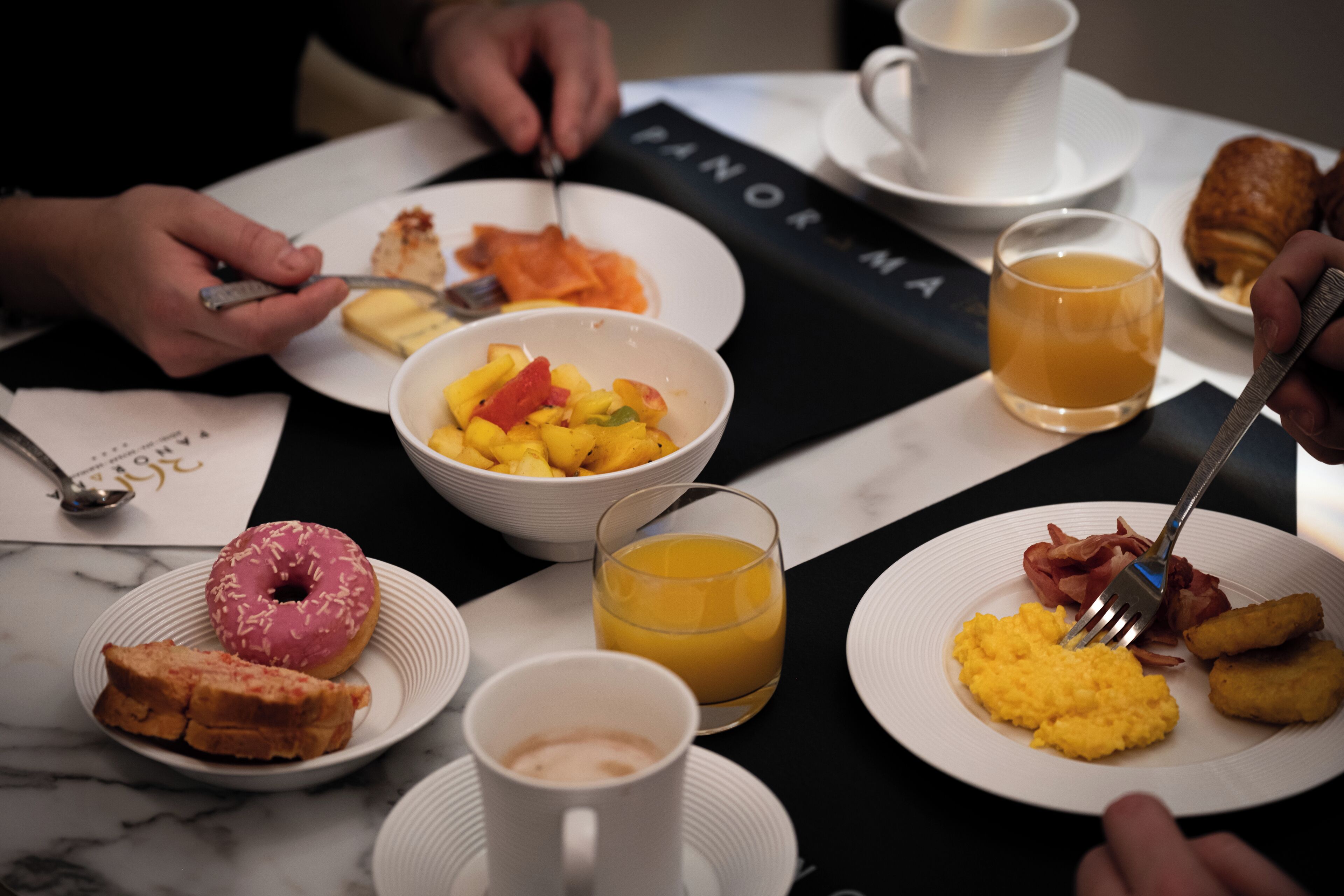 A breakfast setting with plates of food, a donut, and a cup of coffee.
