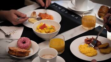 Un desayuno con platos de comida, un donut y una taza de café.