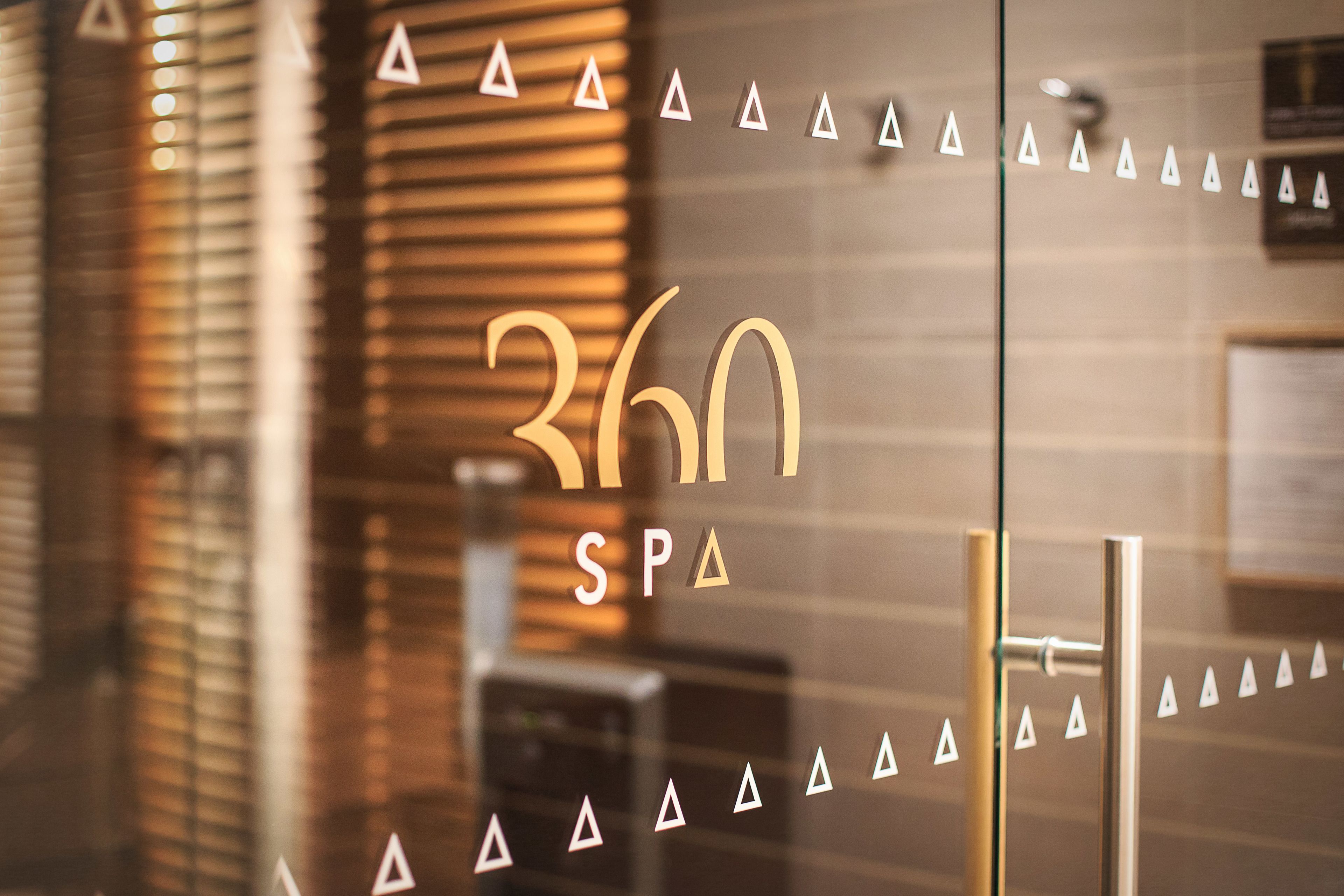 A glass door with the number 360 and the word "SPA" in gold lettering, surrounded by triangular decorations.