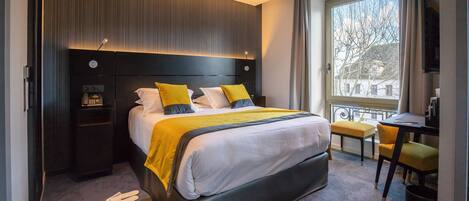 Et moderne hotelværelse med en stor seng, sengeborde, et skrivebord og udsigt ud.