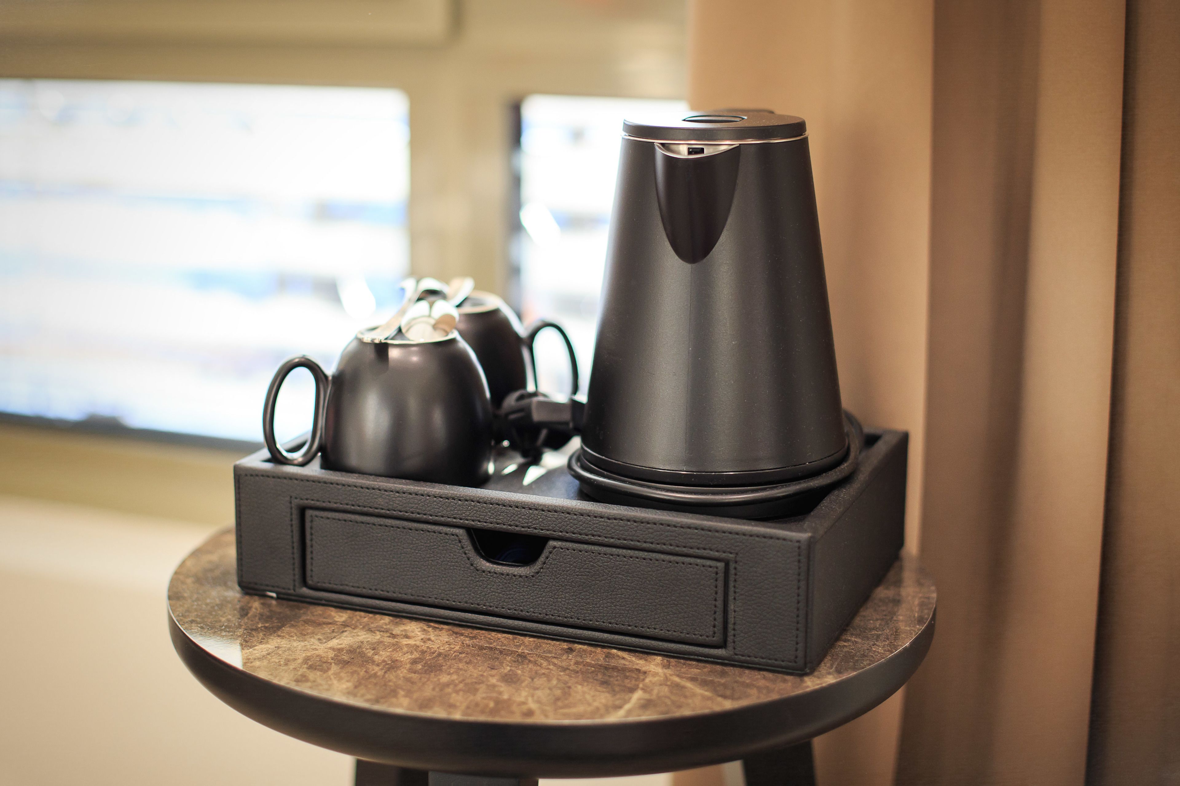 Una estación de café compacta y moderna con una tetera y una cafetera sobre una mesa de mármol.