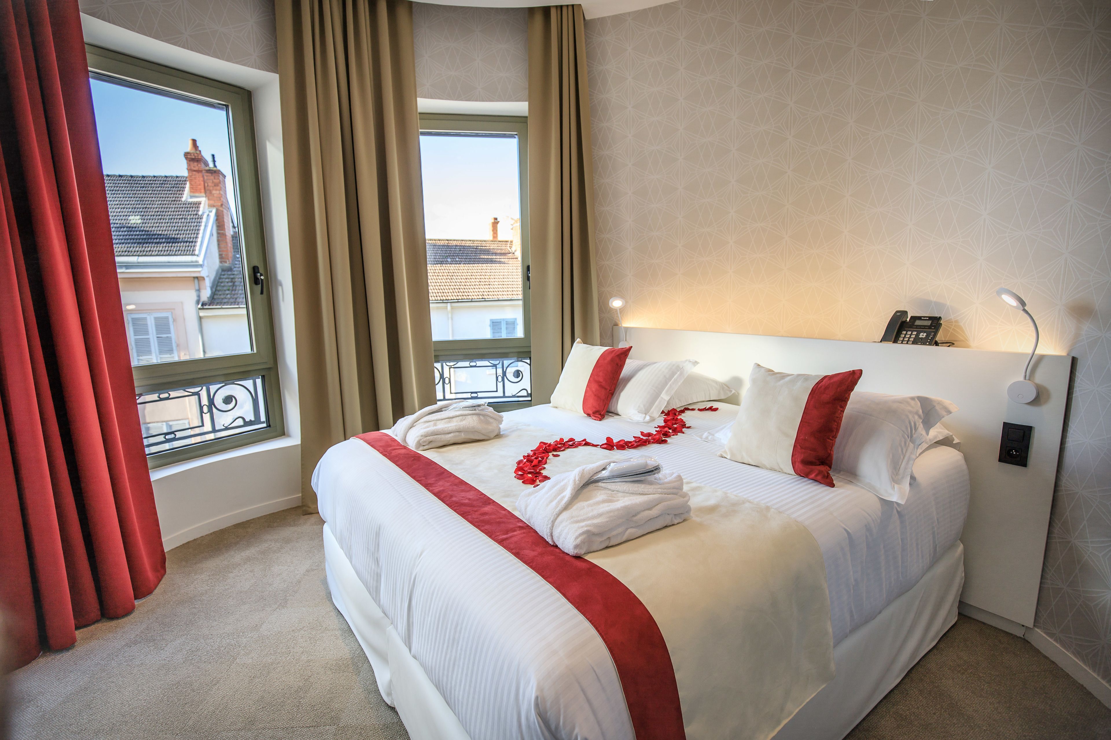 Habitación de hotel con una cama grande, vista de edificios a través de la ventana y un teléfono en la mesita de noche.
