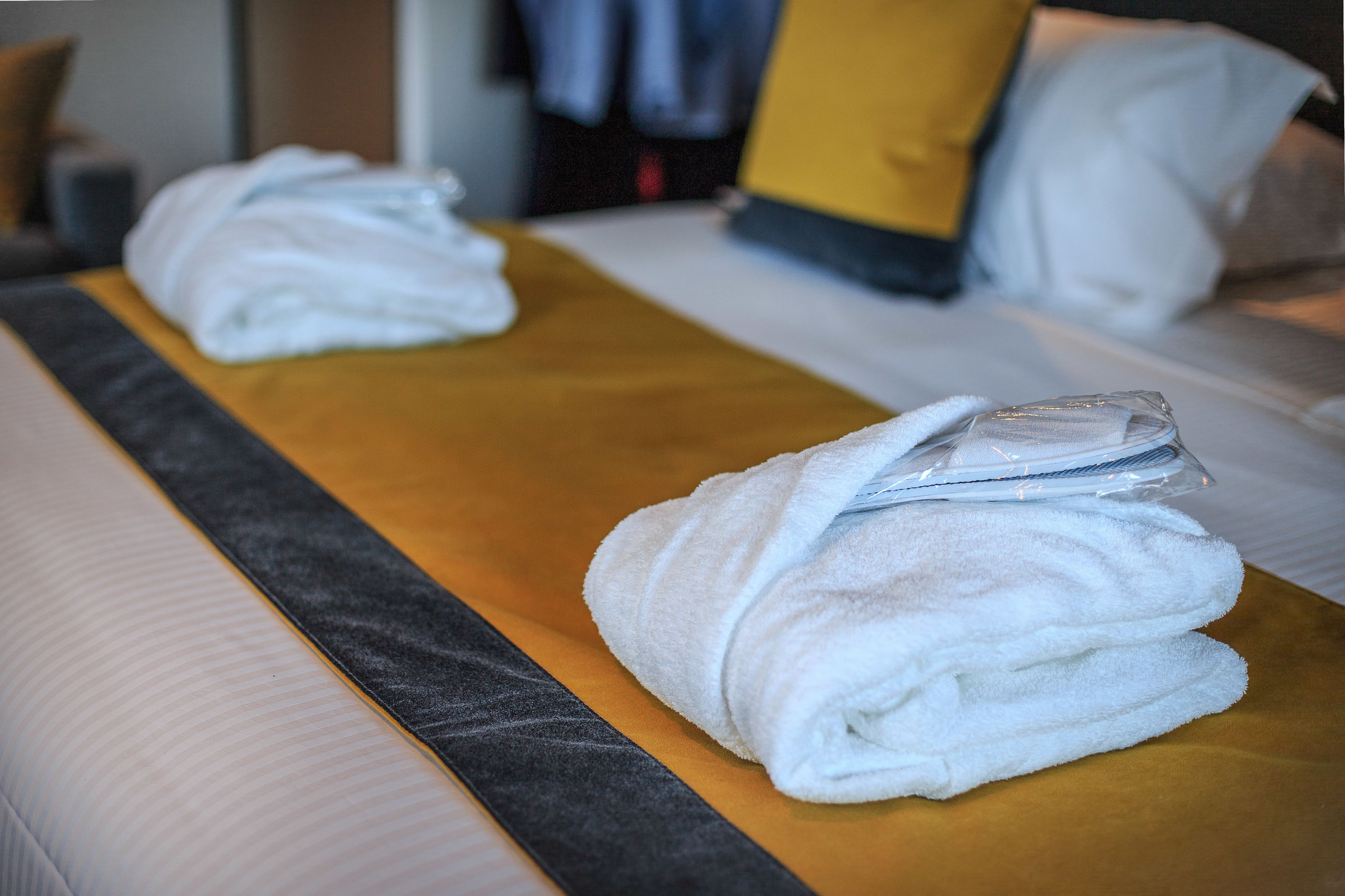 Habitación de hotel con dos camas, cada una con ropa blanca y cabeceros amarillos.