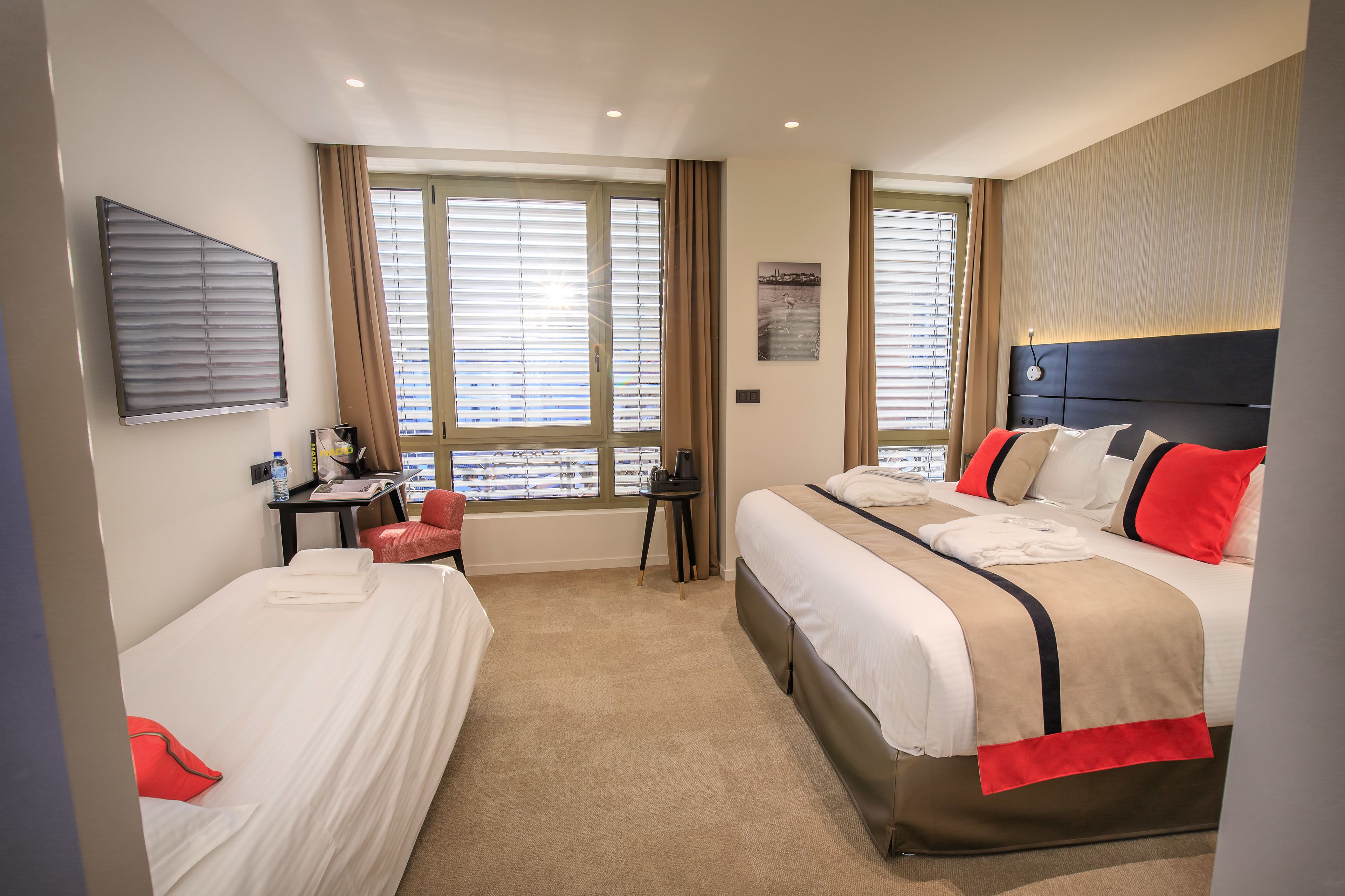 A hotel room with two beds, a desk, and a chair.