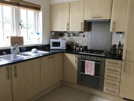 Una cocina con armarios de madera, un microondas, una estufa a gas y un horno.