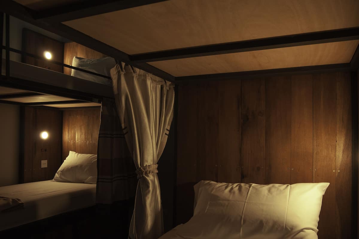 A cabin with two beds, wooden walls, and a curtain.