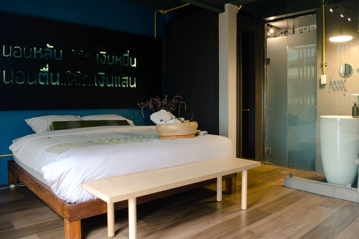 A modern bedroom with a bed, bedside table, and a wall with illuminated text.