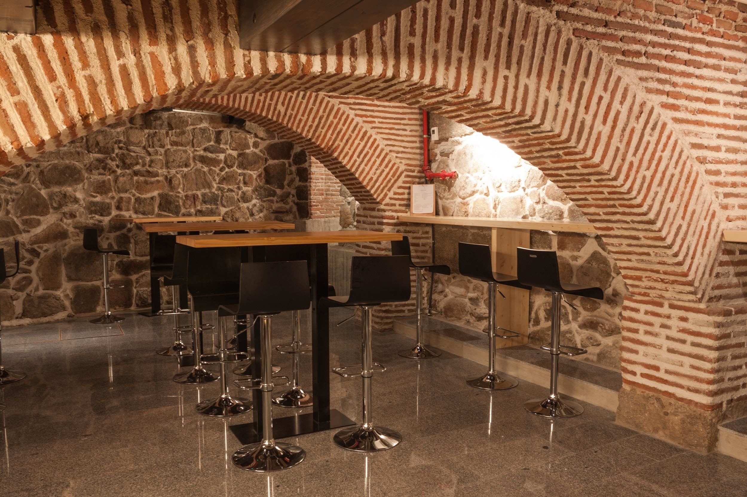 Una zona de bar con paredes de piedra y una barra de madera.