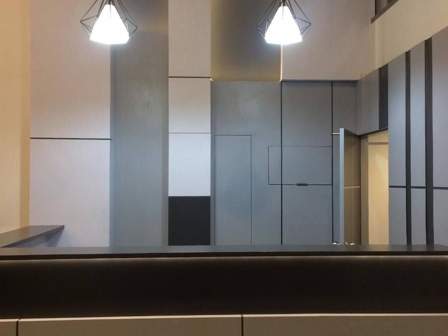 A modern interior with two pendant lights, a dark counter, and a minimalist wall design.