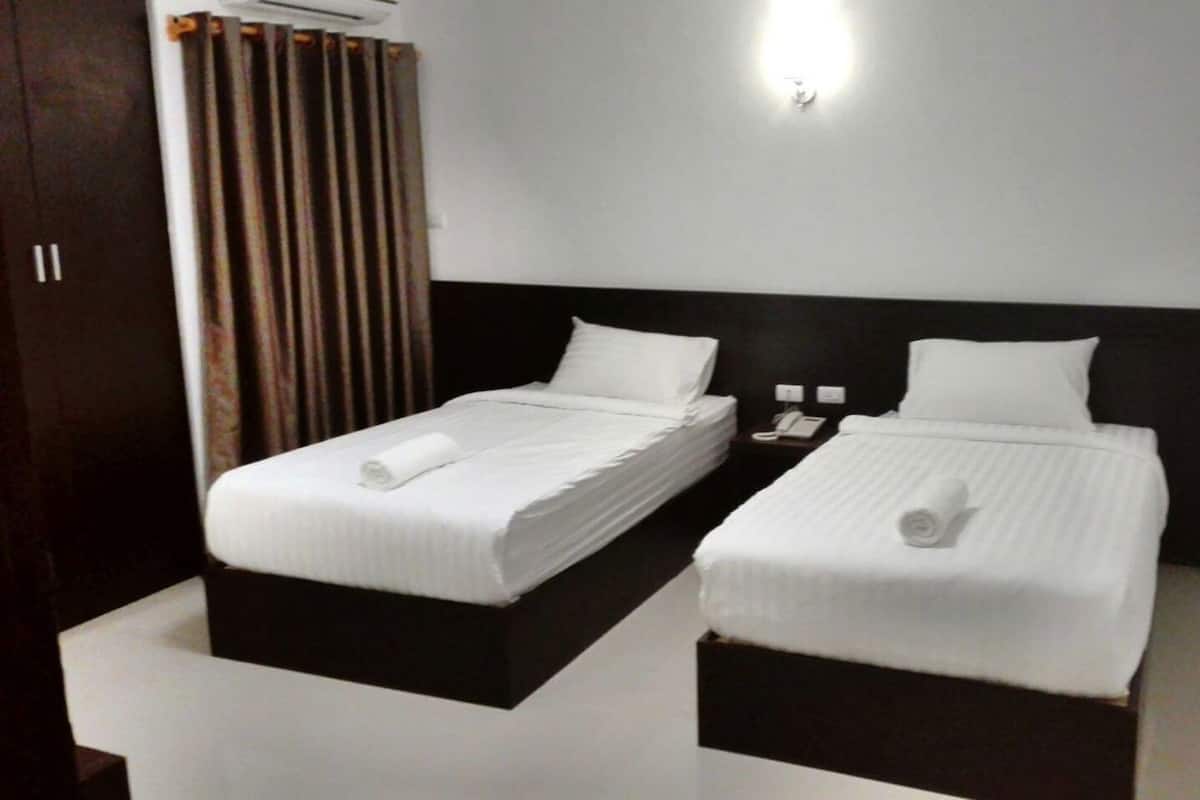 Habitación de hotel con dos camas individuales, una mesita de noche con teléfono y una lámpara de pared.