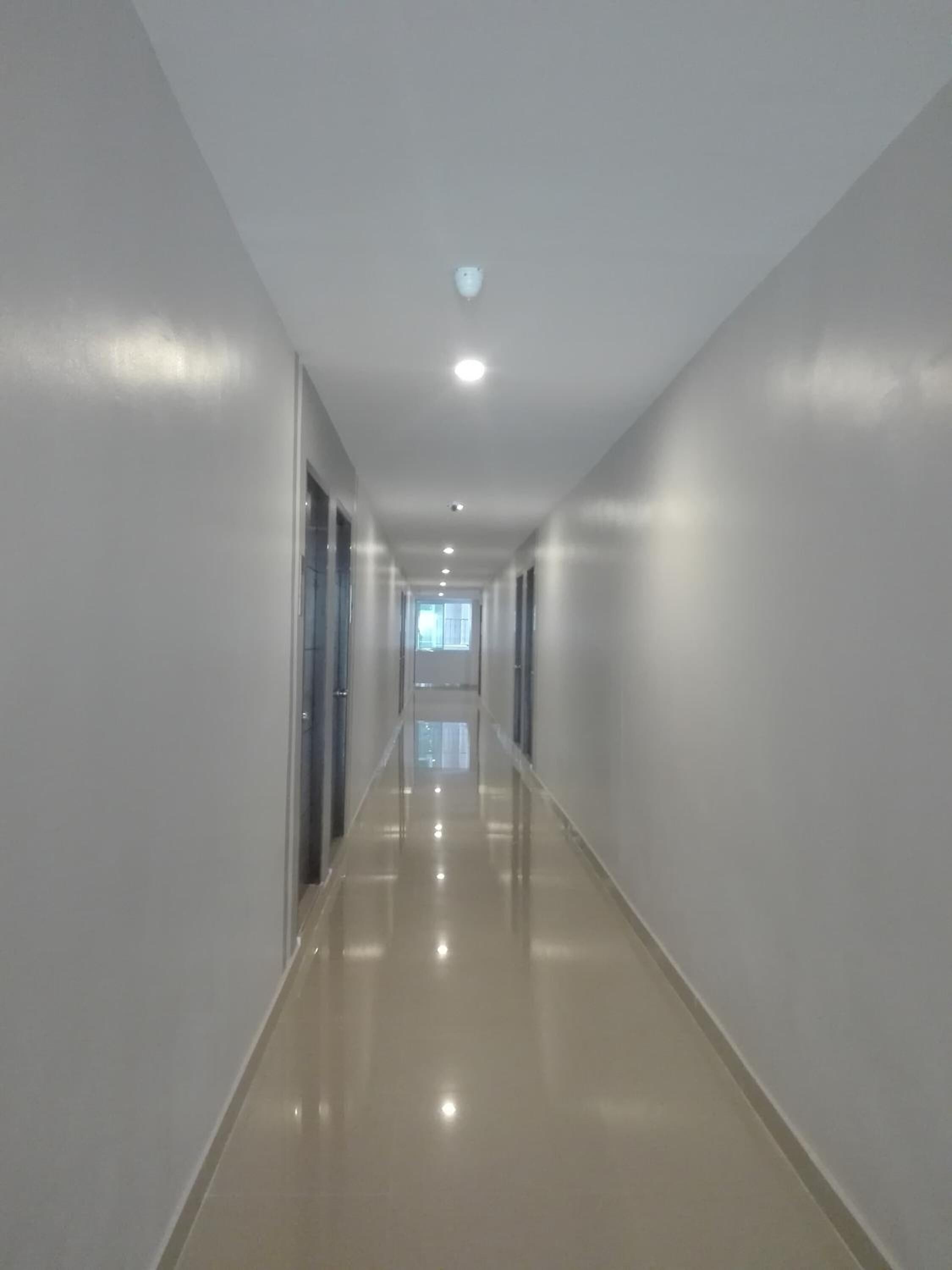 A long, narrow hallway with a shiny floor and white walls.
