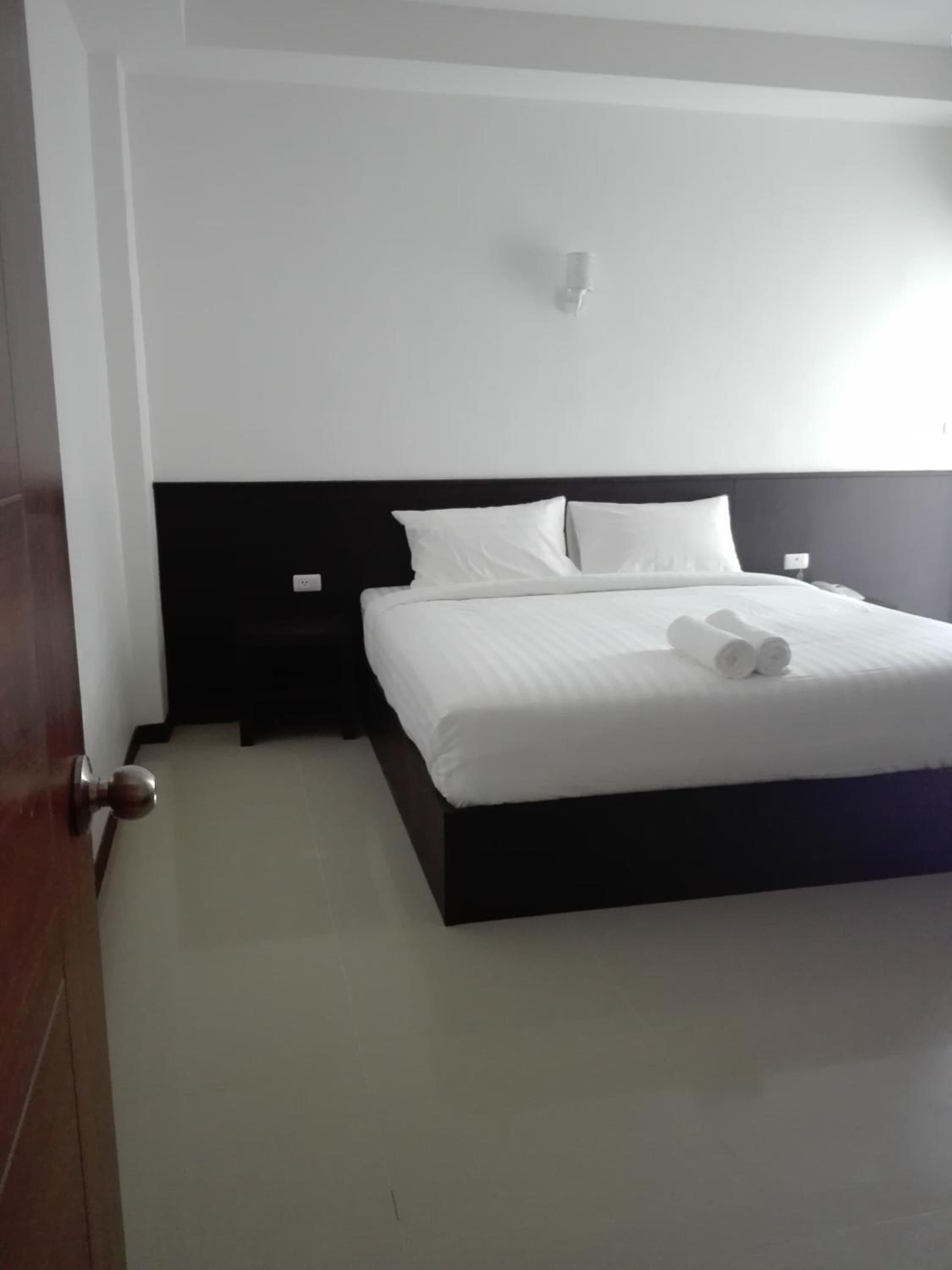 A bedroom with a bed, a nightstand, and a wall-mounted light.