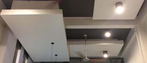 A modern interior with a ceiling fan, recessed lighting, and a glass balcony.