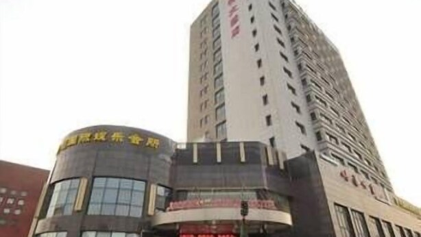 A tall hotel with a modern design, featuring a prominent entrance and a visible signboard. - Junlin Dongfang Hotel (Zhenjiang)