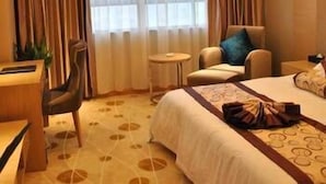 A hotel room with a bed, a desk, a chair, and a small table. - Junlin Dongfang Hotel (Zhenjiang)