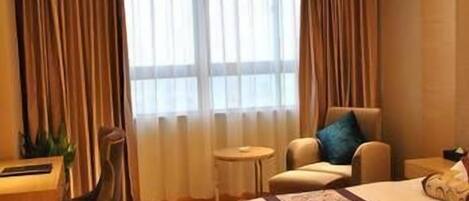 Una habitación de hotel con una cama, un escritorio, una silla y una mesita.