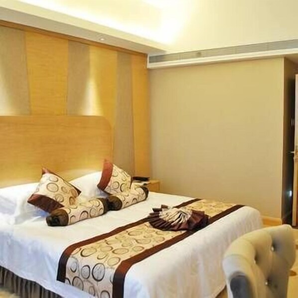 A hotel room with a large bed, a wooden headboard, and a nightstand. - Junlin Dongfang Hotel (Zhenjiang)