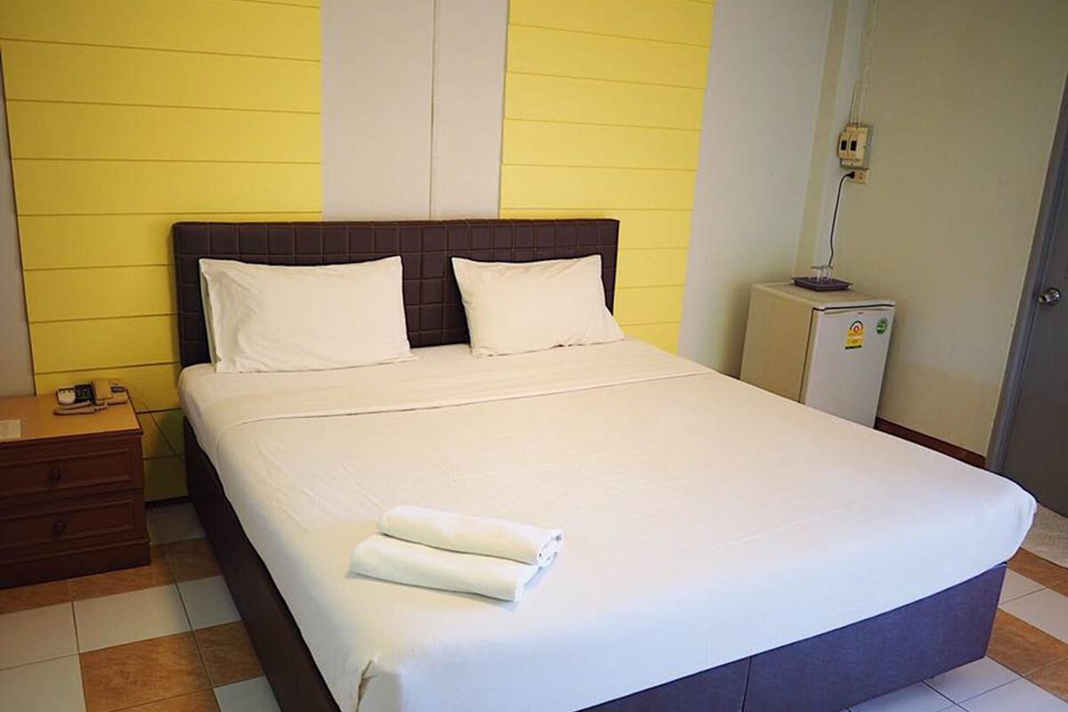 A neatly made bed with white linens, a wooden headboard, and a small bedside table with a lamp.
