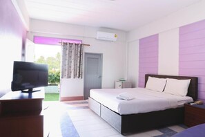 Ein Hotelzimmer mit einem Bett, einem Fernseher auf einem Tisch, einem kleinen Tisch und einem Fenster mit Vorhängen.