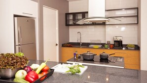 Eine moderne Küche mit Kühlschrank, Herd, Spüle und einer Auswahl frischer Gemüsesorten auf der Arbeitsfläche.