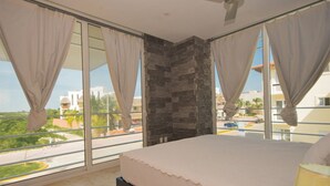 Ein Schlafzimmer mit einem großen Bett, einer Wand aus Stein und einem Balkon mit Vorhängen.