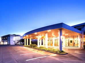 A hotel entrance with a covered waiting area, columns, and a parking lot. - Kujyukushima Seaside Terrace Hotel & Spa Hanamizuki (Sasebo)