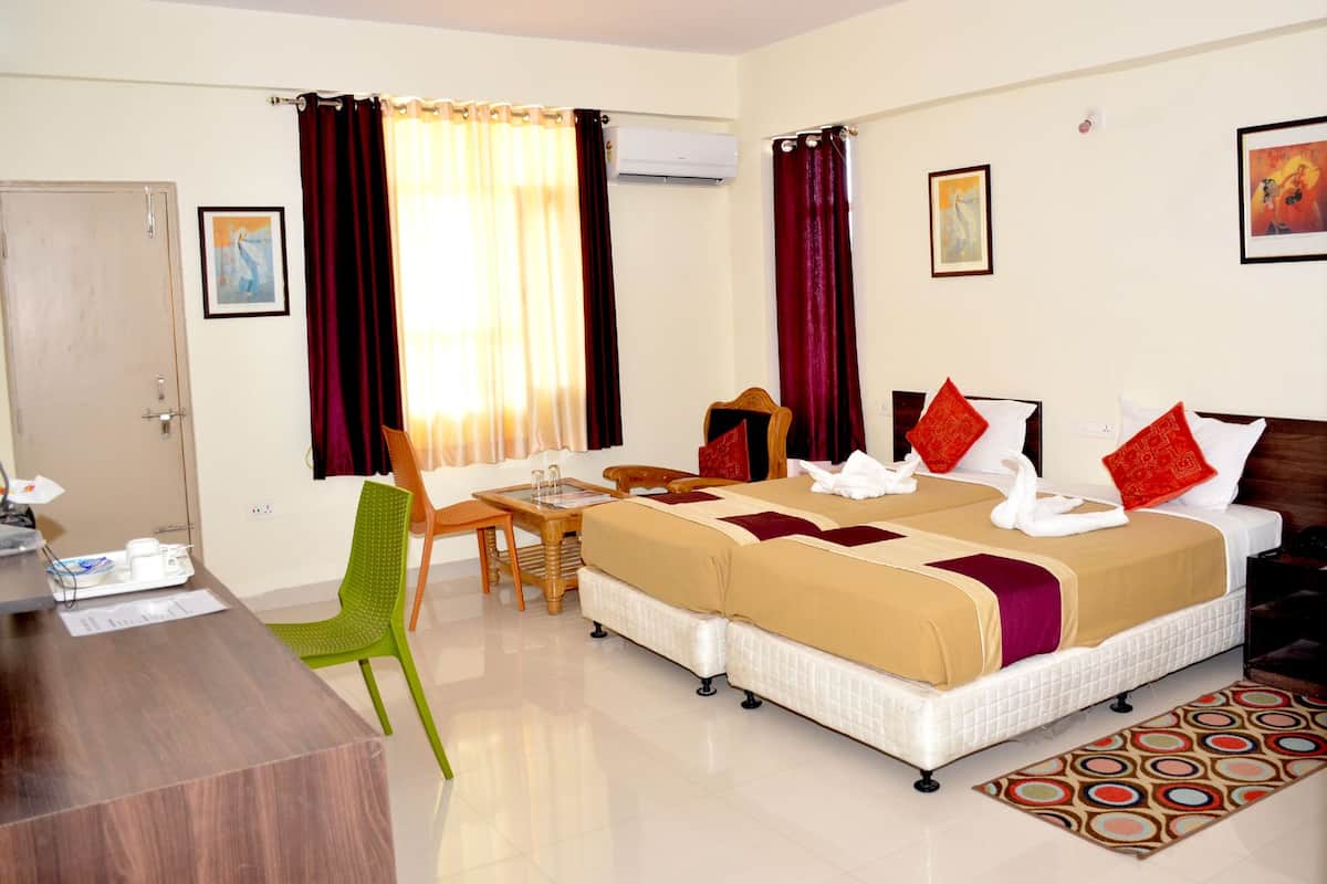 Habitación de hotel con una cama, dos sillas, un escritorio y una mesita.