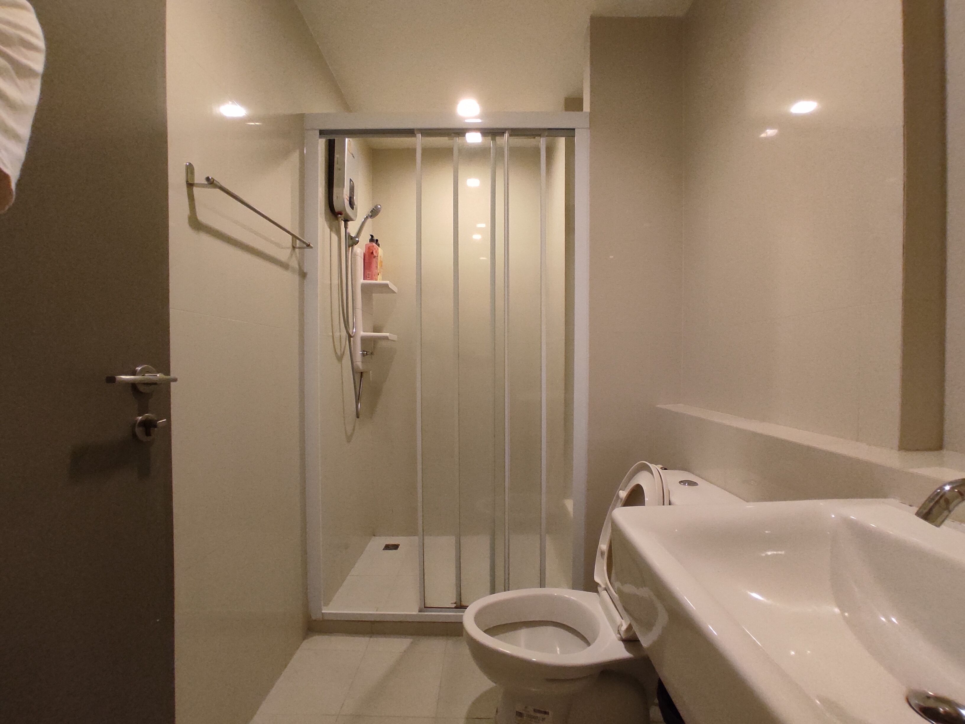 A modern bathroom with a glass-enclosed shower, a toilet, and a large sink with a mirror.
