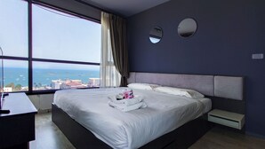 Ein Hotelzimmer mit einem großen Bett, einem Schreibtisch und Meerblick.