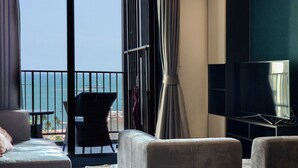 Ein Zimmer mit Balkon, Fernseher und Sitzgelegenheit.
