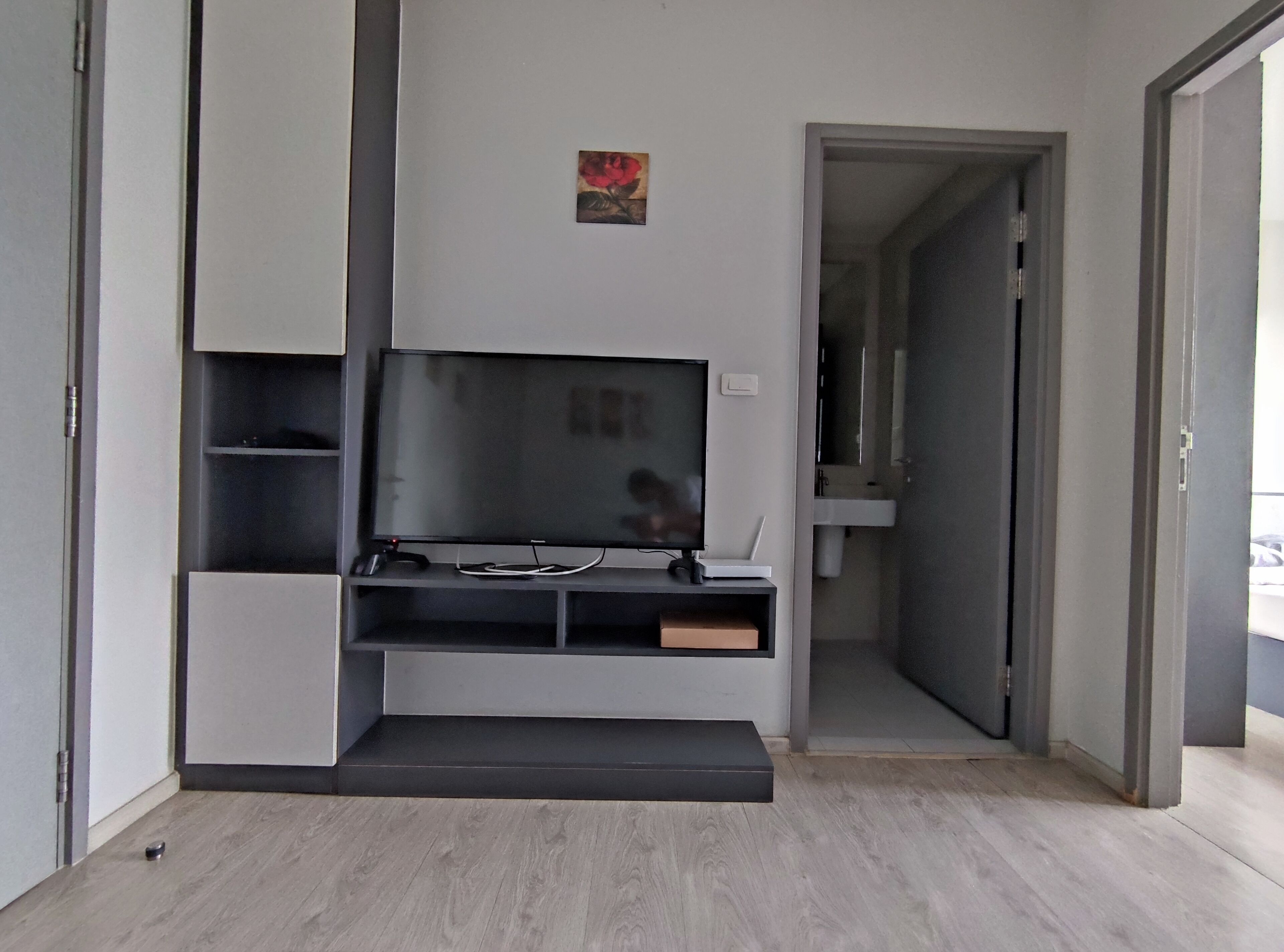 Un salon moderne doté d’un téléviseur à écran plat, d’étagères intégrées et d’une petite œuvre d’art accrochée au mur.