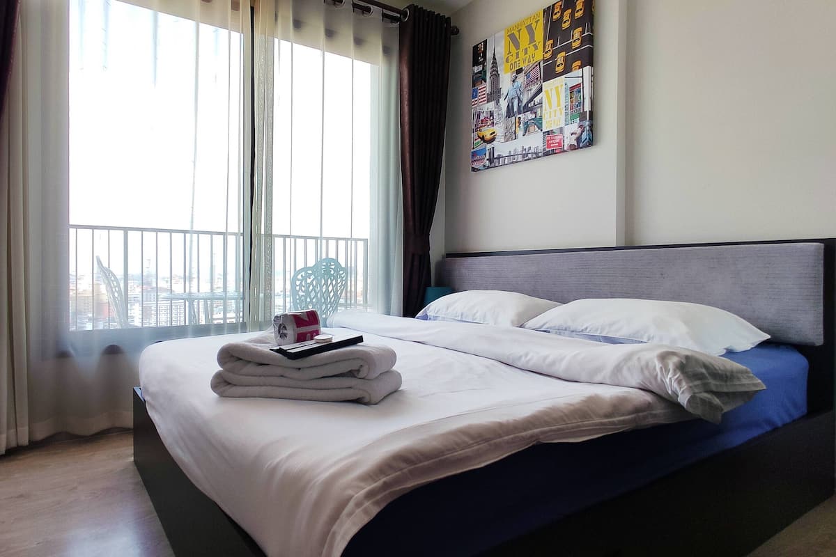A hotel room with a bed, a desk, and a window with curtains.