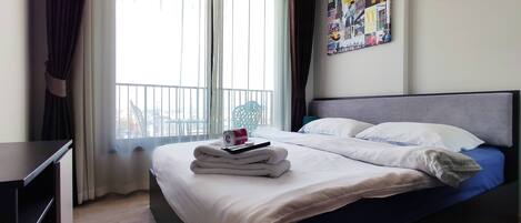 A hotel room with a bed, a desk, and a window with curtains.