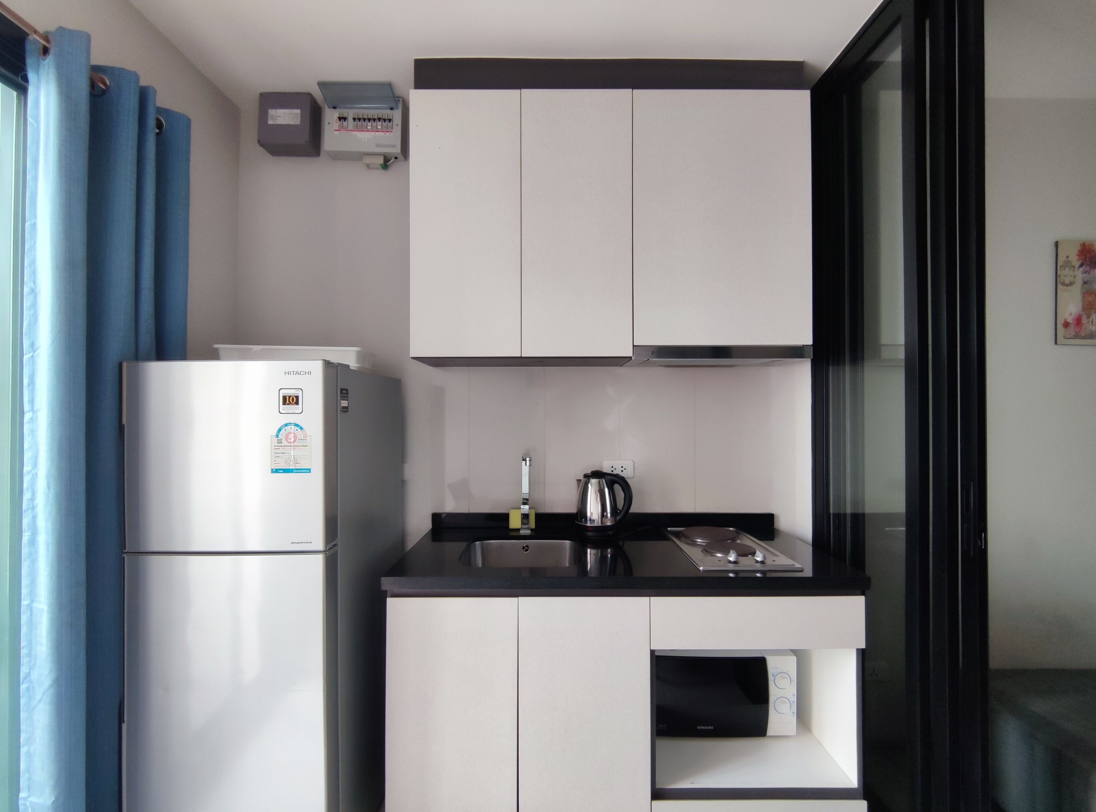 Eine kleine Küche mit Kühlschrank, Wasserkocher und Mikrowelle.
