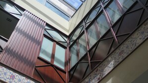 A modern building with large windows and a decorative tile border. - Posada Pilatos (Seville)