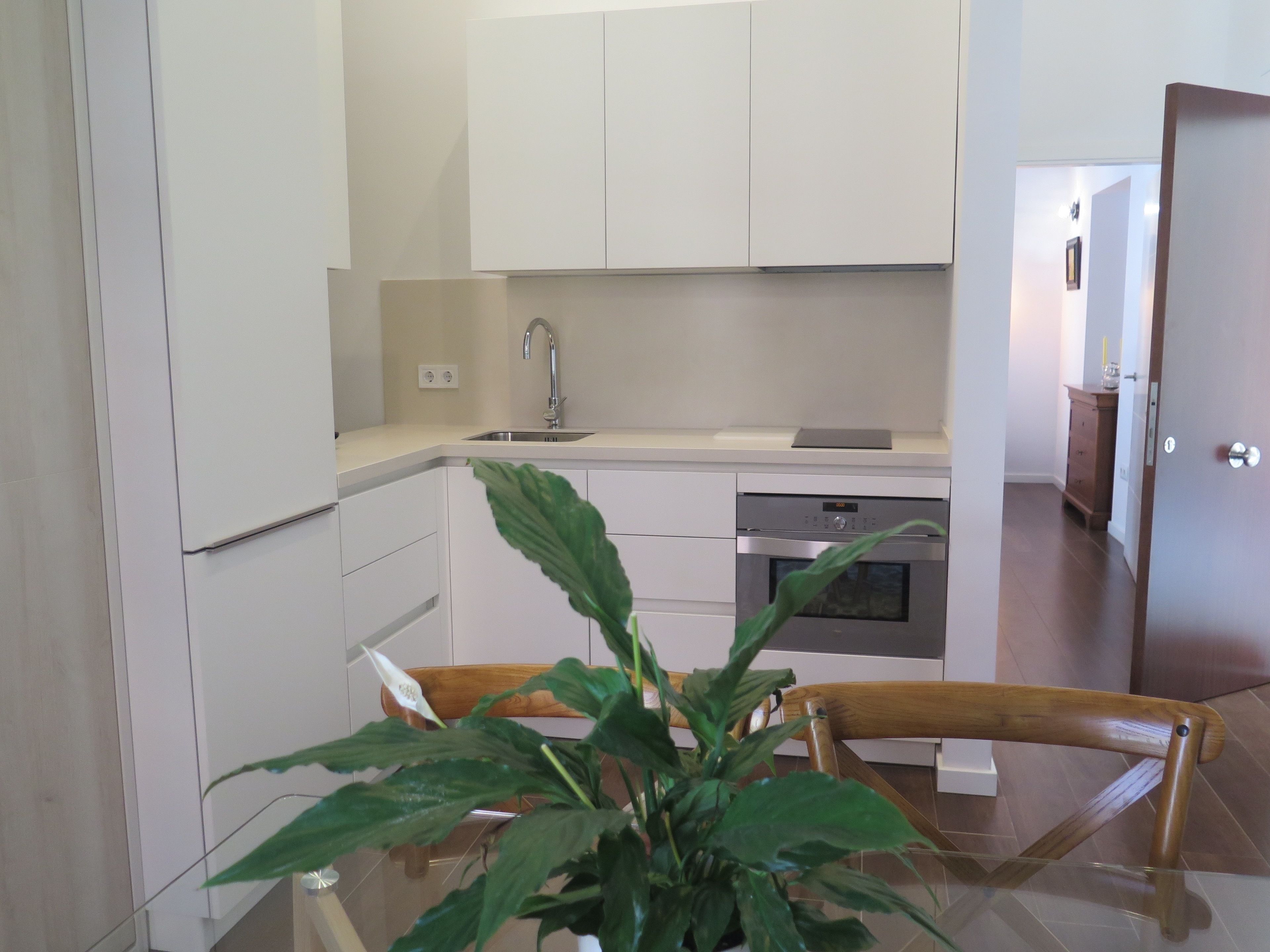 A modern kitchen with white cabinets, a stainless steel sink, and an oven.