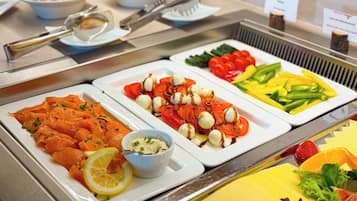 A buffet with various food options including salmon, tomatoes, and vegetables.