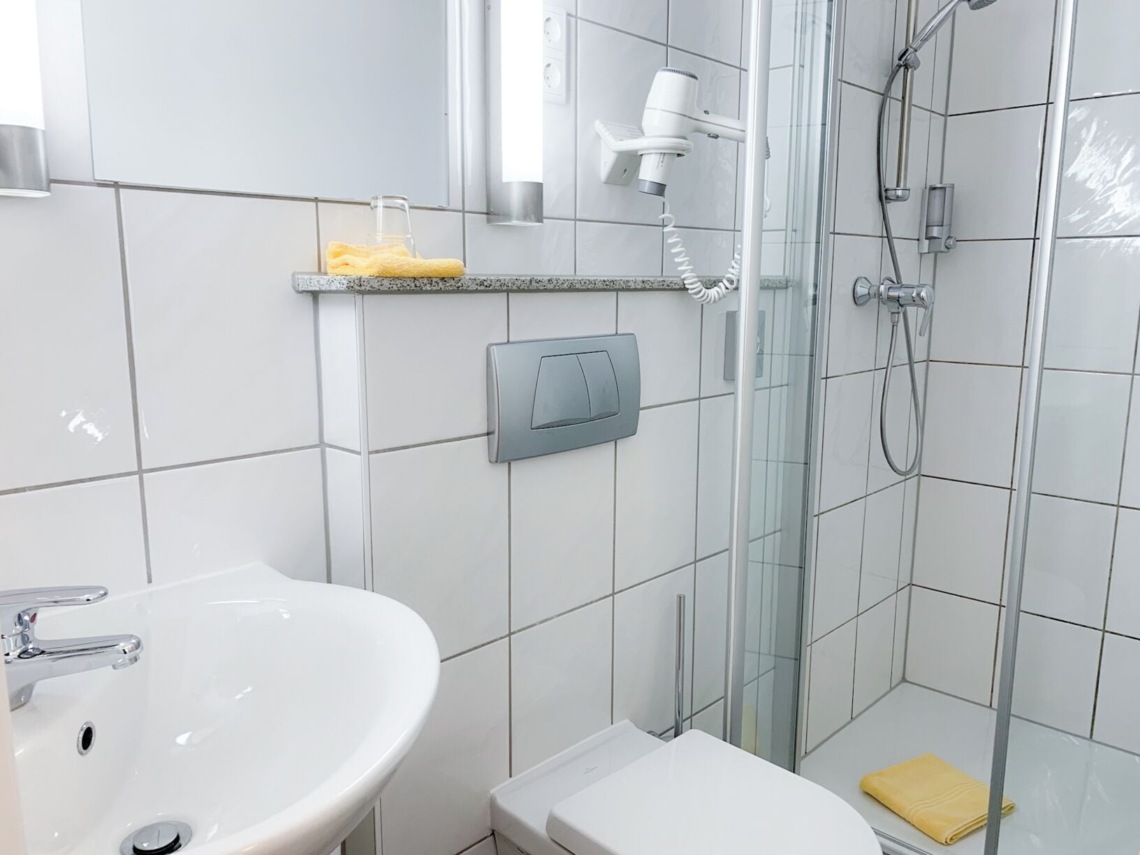 Ein modernes Badezimmer mit Waschbecken, Toilette und Duschbereich in Weiß.