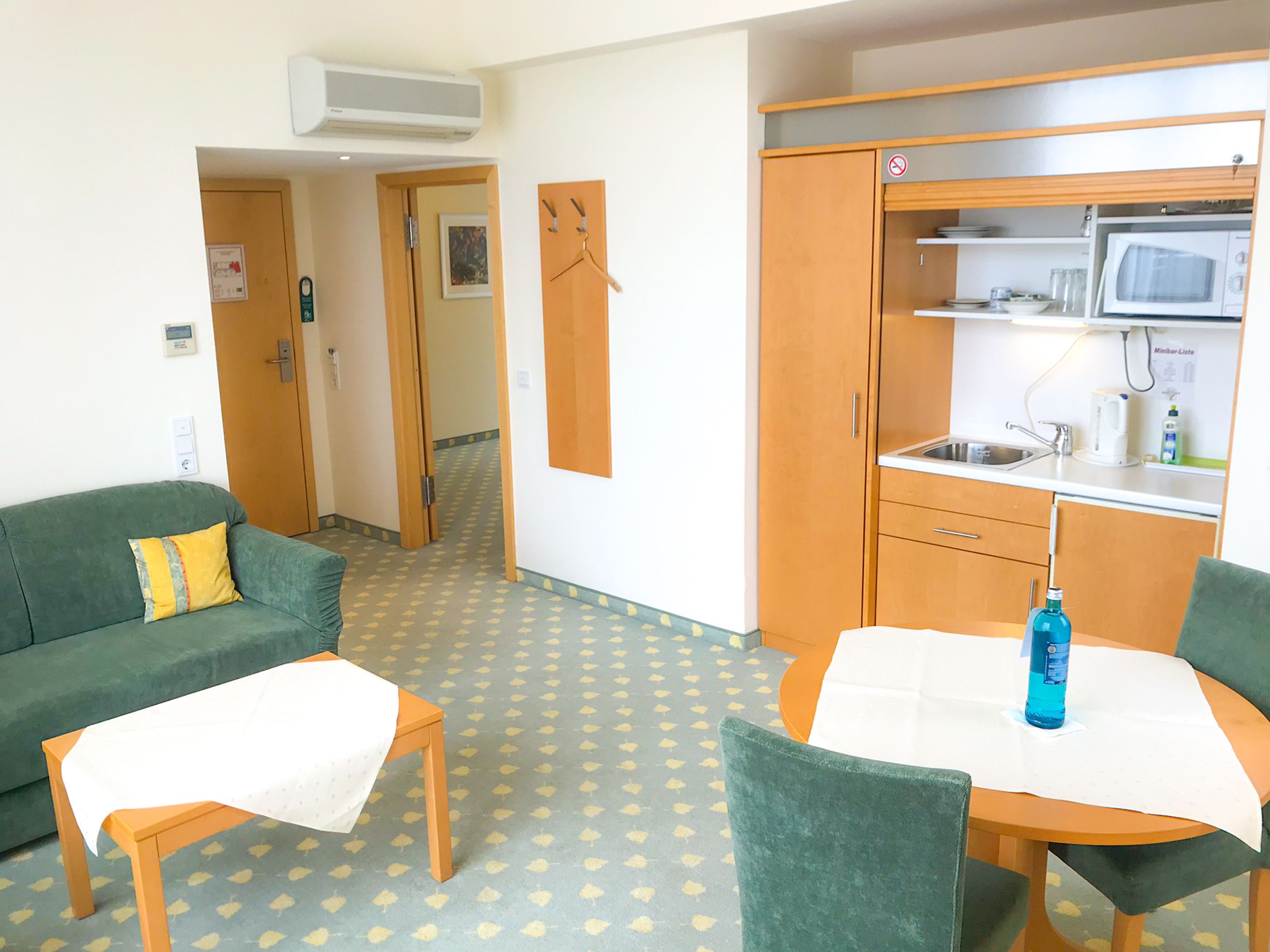 A compact living space with a kitchenette, a sofa, a dining table, and a small table.