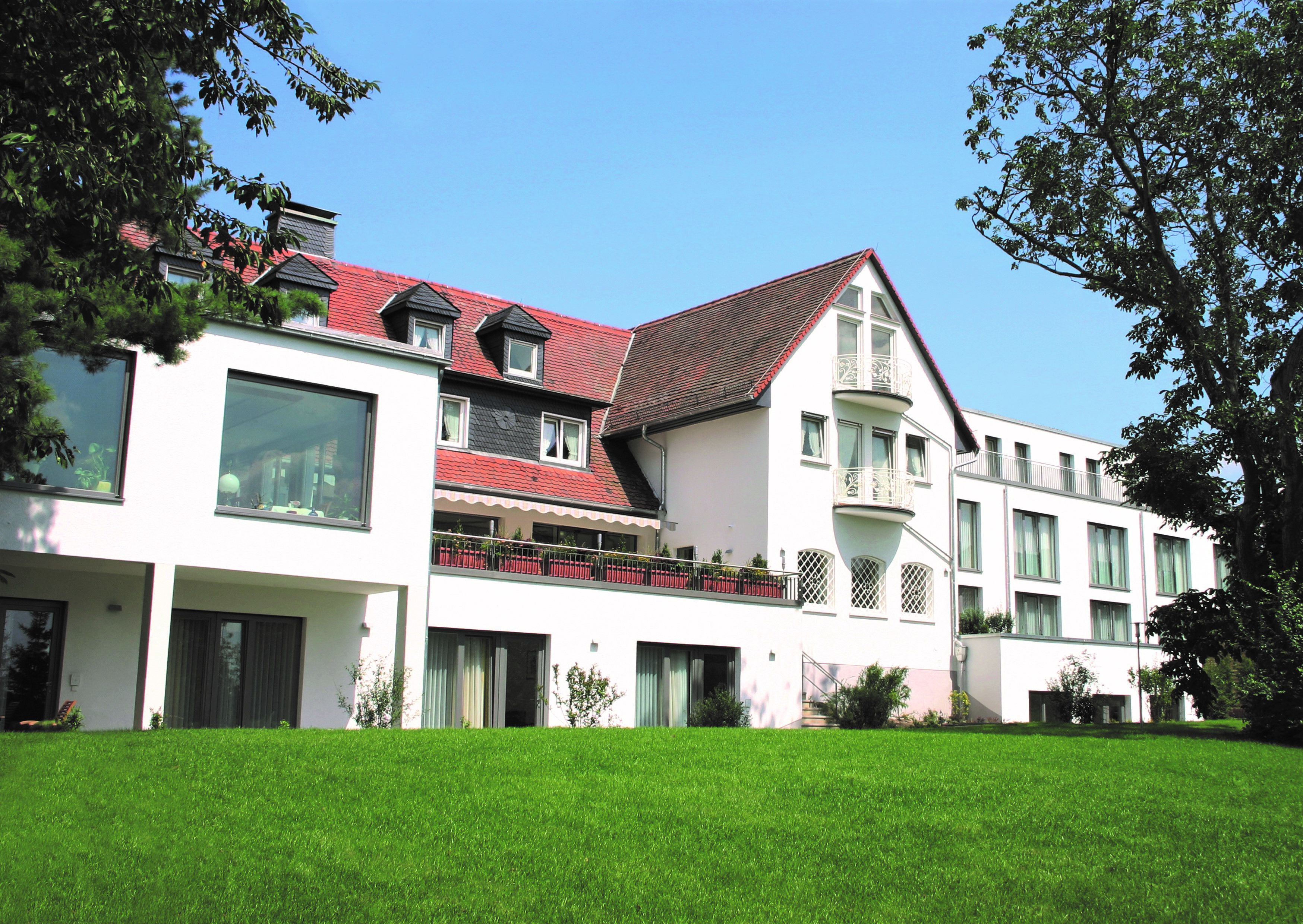 A multi-story hotel with a red-tiled roof, large windows, and a well-maintained lawn.