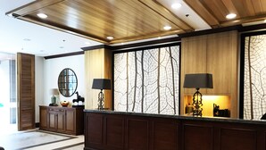 A reception area with a wooden ceiling, a marble floor, and a large window with a tree pattern.