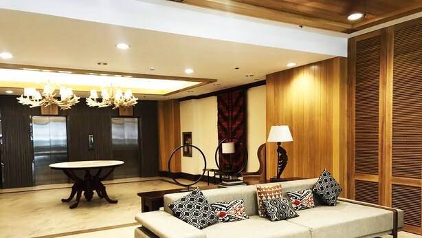 A modern living room with a sofa, patterned cushions, a round table, and a chandelier.