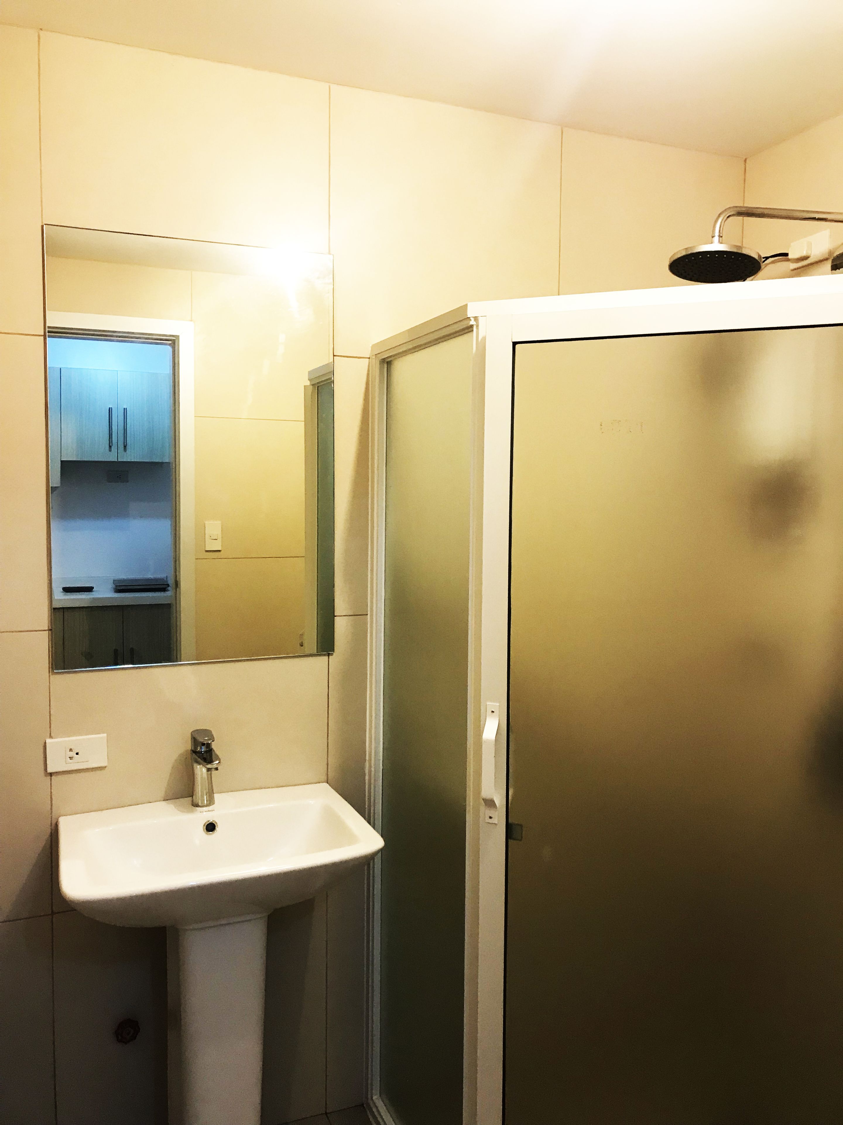 A bathroom with a white sink, a mirror, and a shower enclosure.
