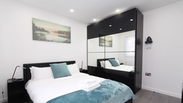 Un dormitorio moderno con una cama grande, una mesita de noche, un espejo y un cuadro en la pared.